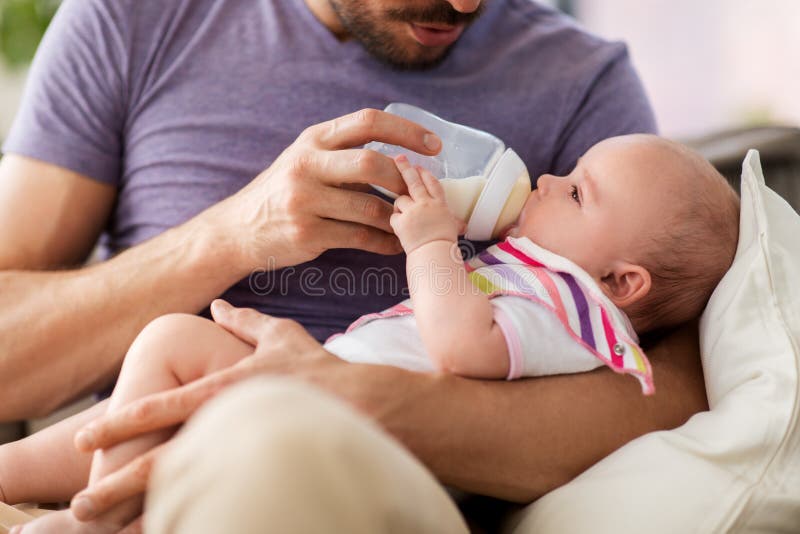 Schließen Sie oben von Fütterungsbaby des Vaters von der Flasche lizenzfreie stockbilder Schließen Sie oben von Fütterungsbaby des Vaters von der Flasche lizenzfreie stockbilder
