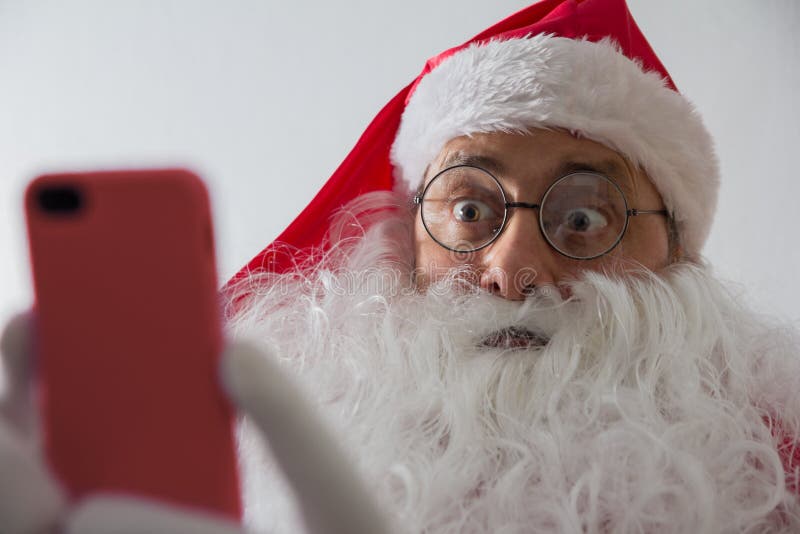 Schließen Sie oben von Santa Claus-Holding Smartphone und vom Schauen überrascht lizenzfreie stockfotos Schließen Sie oben von Santa Claus-Holding Smartphone und vom Schauen überrascht lizenzfreie stockfotos