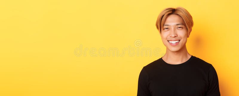 Schließung eines ansehnlichen, stylischen Asiaten mit feinem Haar, der fröhlich über gelbem Hintergrund lächelt stockfoto