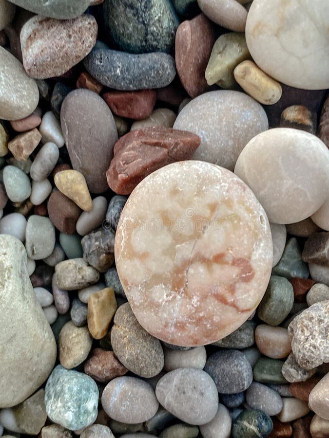 Schließung von Strandkies mit einem großen runden rosa Stein in der Mitte und natürlichen strukturierten Felsen um sie herum lizenzfreie stockfotos