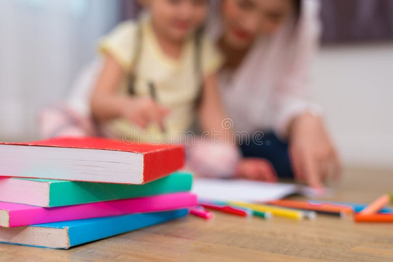 Schließen Sie oben von den Büchern auf Boden mit Mutter- und Kinderhintergrund Zurück zu lizenzfreie stockfotografie