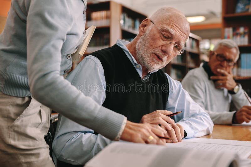 Schließen Sie oben von einem Lektor, der einen älteren Studenten in Klassenzimmer führt stockfoto Schließen Sie oben von einem Lektor, der einen älteren Studenten in Klassenzimmer führt stockfoto