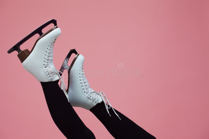 Figure skating is a winter sport and leisure. Women`s feet in ice dancing skates. Female figure skater, legs on a pink background. Figure skating is a winter sport and leisure. Women`s feet in ice dancing skates. Female figure skater, legs on a pink background.