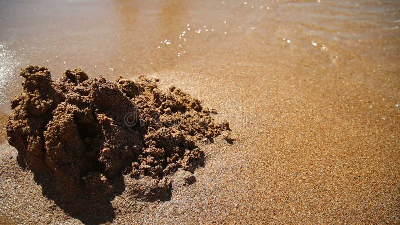 Schloss auf dem Sand wird weg durch eine Seewelle gewaschen