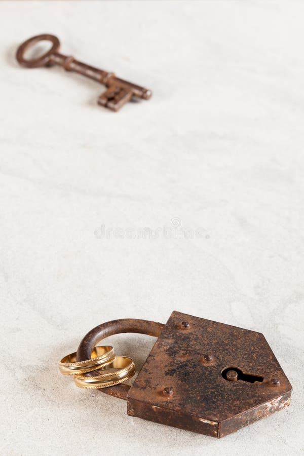 Rusty old padlock with key and wedding rings. Rusty old padlock with key and wedding rings