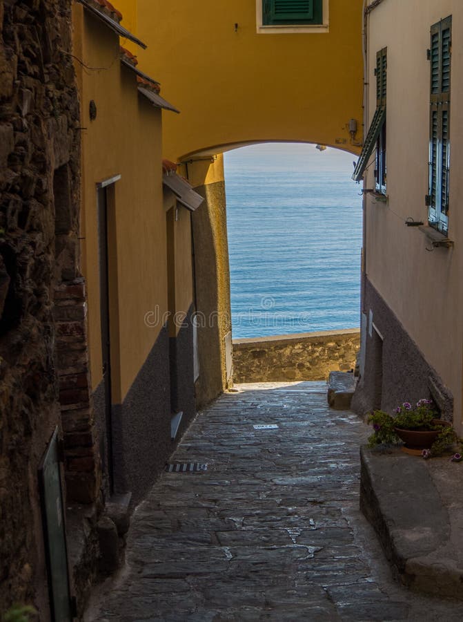 Charming narrow street with view on the sea in Corniglia, Cinque Terre, Liguria, Italy. UNESCO World Heritage Site. Charming narrow street with view on the sea in Corniglia, Cinque Terre, Liguria, Italy. UNESCO World Heritage Site