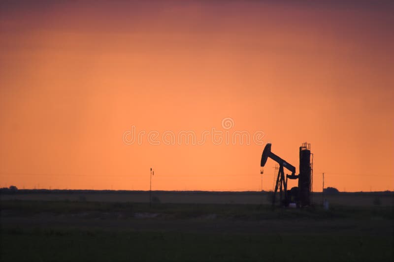 Silhouette of active oil pump shot at sunset west of Lubbock, Texas, USA. Silhouette of active oil pump shot at sunset west of Lubbock, Texas, USA