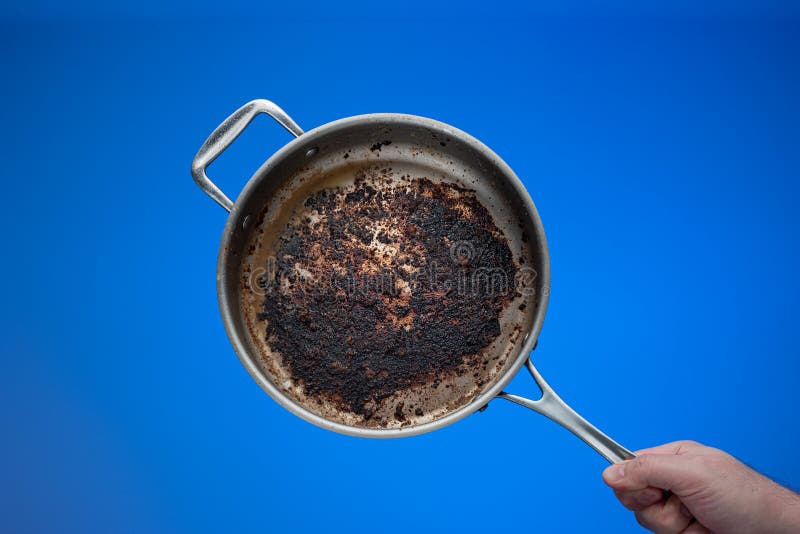 Dirty oily burnt metal frying pan held in hand by male hand. Dirty oily burnt metal frying pan held in hand by male hand.