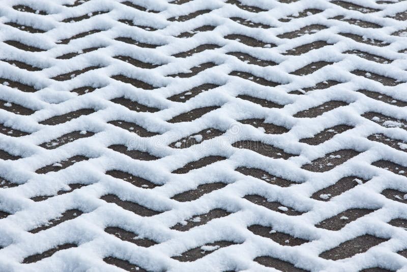 Melting snow on a herringbone paved driveway. Melting snow on a herringbone paved driveway