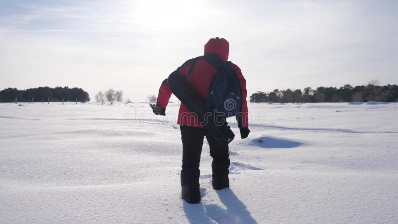 Schneiende Winterabdrücke des Mannes Konzeptreise, die Schwierigkeiten überwindt Wanderer in einer Winterabendebene bei dem Sonne