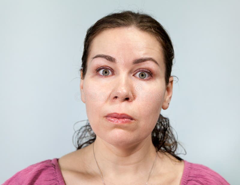 Schock und Erstaunen auf dem Gesicht einer erwachsenen Frau, Augen weit offen, Portrait auf grauem Hintergrund, Emotionen Serie lizenzfreies stockfoto