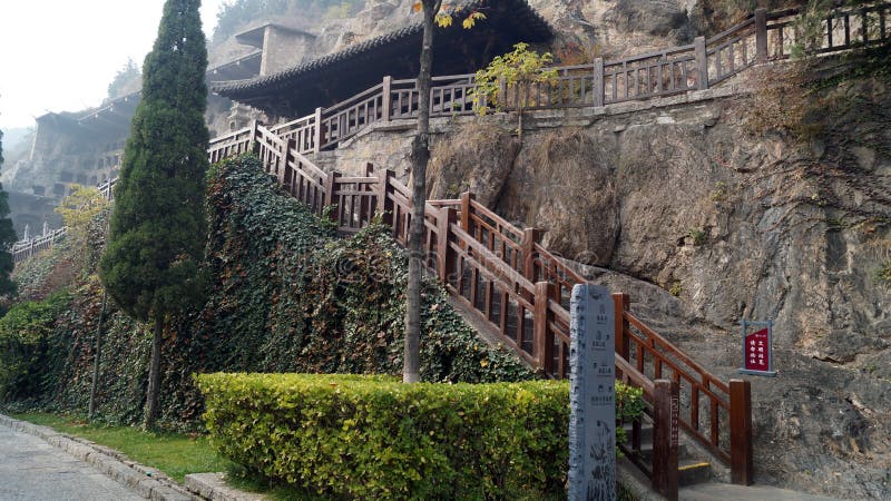 Longmen grottoes with several niches carved in the wall at the face of a mountain, buddhist temple whit several sculptures in it, entrance stairs. Longmen grottoes with several niches carved in the wall at the face of a mountain, buddhist temple whit several sculptures in it, entrance stairs