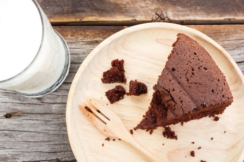 Schokoladenkuchen auf hölzerner Platte mit einem Glas Milch stockfoto Schokoladenkuchen auf hölzerner Platte mit einem Glas Milch stockfoto