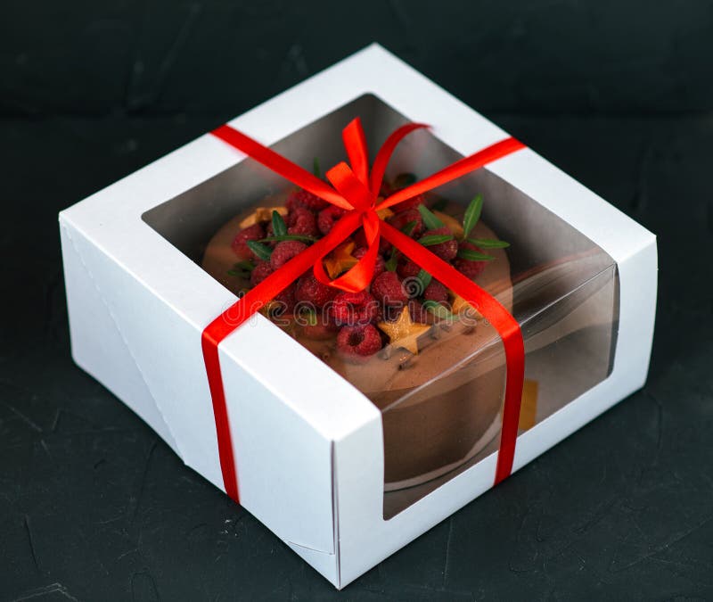 Schokoladenkuchen in einem weißen Kasten mit einem roten Bogen Auf einem schwarzen Hintergrund Inkompetent mit Himbeeren und Keks lizenzfreies stockfoto Schokoladenkuchen in einem weißen Kasten mit einem roten Bogen Auf einem schwarzen Hintergrund Inkompetent mit Himbeeren und Keks lizenzfreies stockfoto