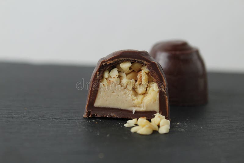 Schokoladenkuchen in Sektion mit Pralinen Erdnüssen auf grauem Hintergrund zerkleinert. ein Tag Schokolade ohne Diät lizenzfreie stockfotografie