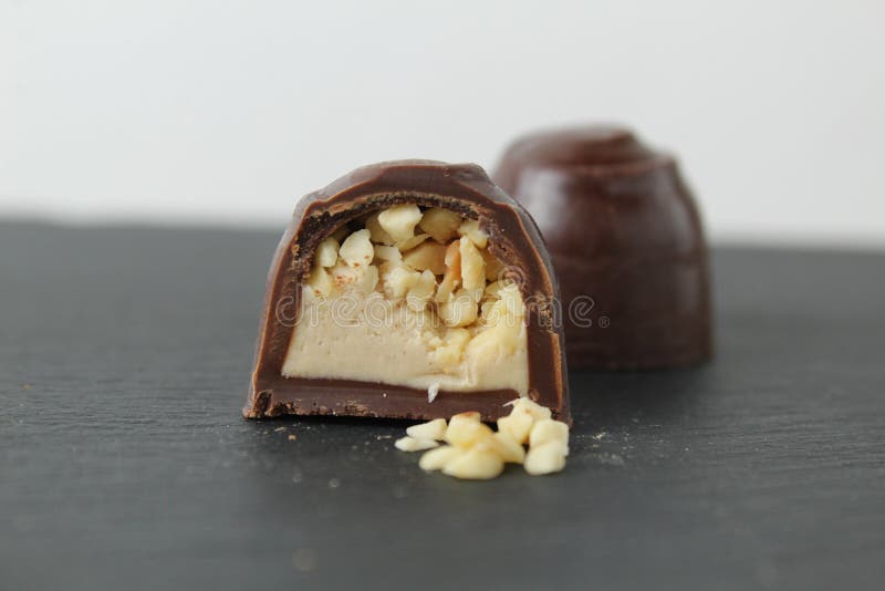 Schokoladenkuchen in Sektion mit Pralinen Erdnüssen auf grauem Hintergrund zerkleinert. ein Tag Schokolade ohne Diät stockbilder