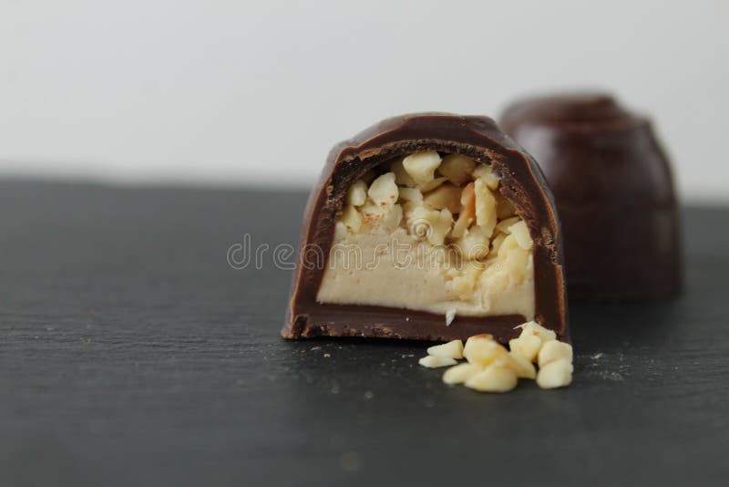 Schokoladenkuchen in Sektion mit Pralinen Erdnüssen auf grauem Hintergrund zerkleinert. ein Tag Schokolade ohne Diät stockfotos