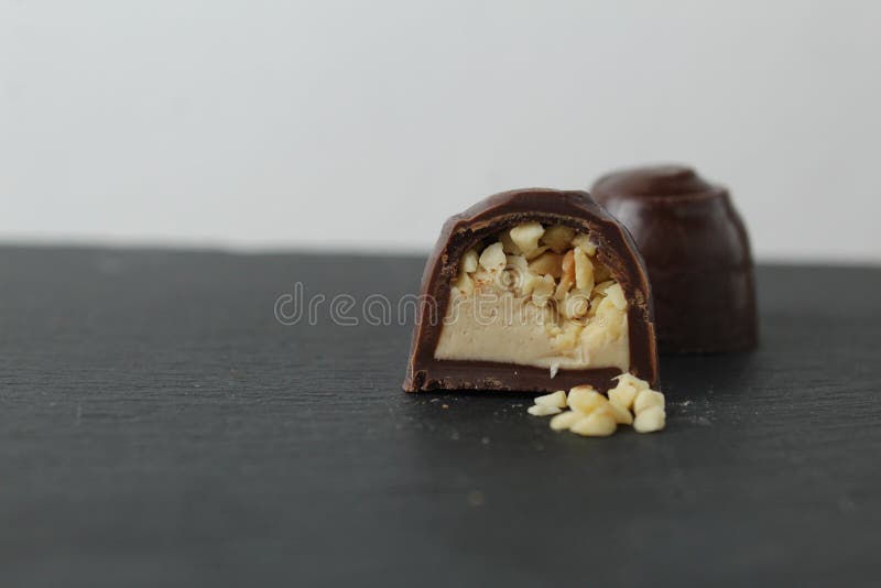 Schokoladenkuchen in Sektion mit Pralinen Erdnüssen auf grauem Hintergrund zerkleinert. ein Tag Schokolade ohne Diät lizenzfreie stockfotos