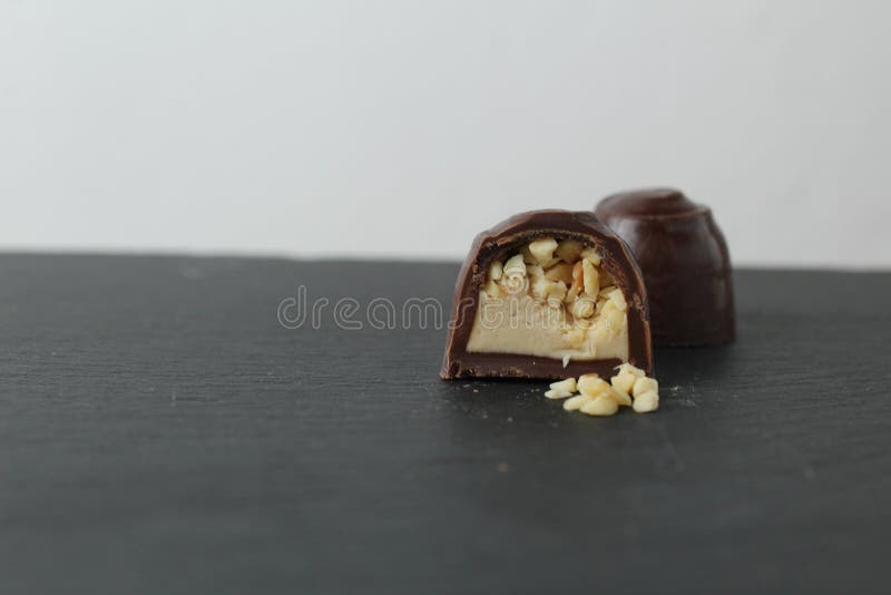 Schokoladenkuchen in Sektion mit Pralinen Erdnüssen auf grauem Hintergrund zerkleinert. ein Tag Schokolade ohne Diät stockbild