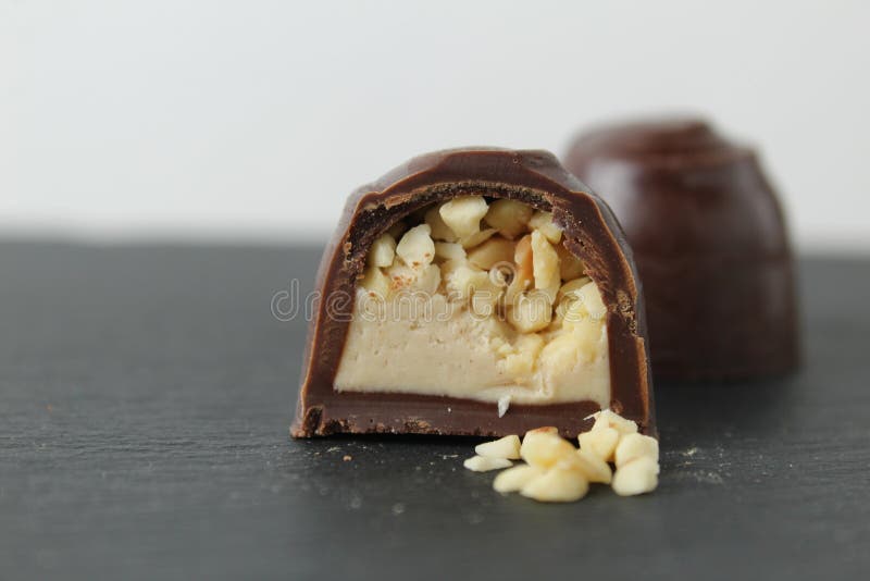 Schokoladenkuchen in Sektion mit Pralinen Erdnüssen auf grauem Hintergrund zerkleinert. ein Tag Schokolade ohne Diät lizenzfreie stockbilder