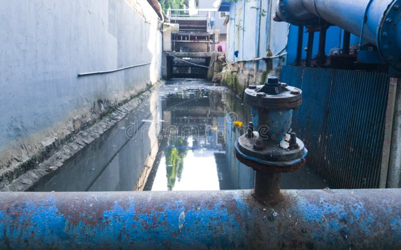 a clean tap water pipe crossing over dirty river in Jakarta, Indonesia. a clean tap water pipe crossing over dirty river in Jakarta, Indonesia