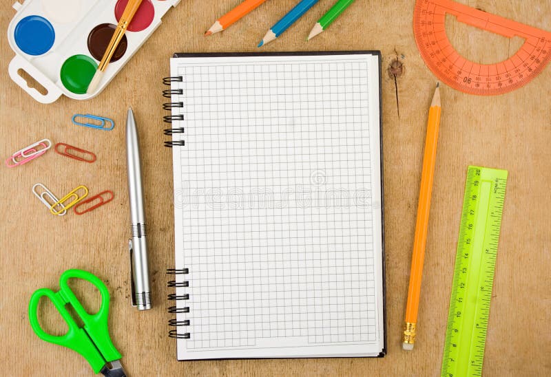 School accessories and checked notebook on wood