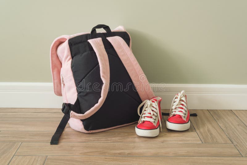 School backpack and sneakers on the floor in home interior stock images