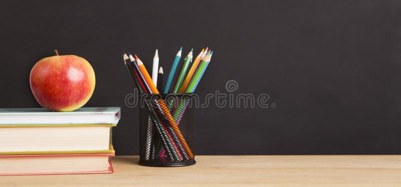 School books, apple and pencils over chalkboard background