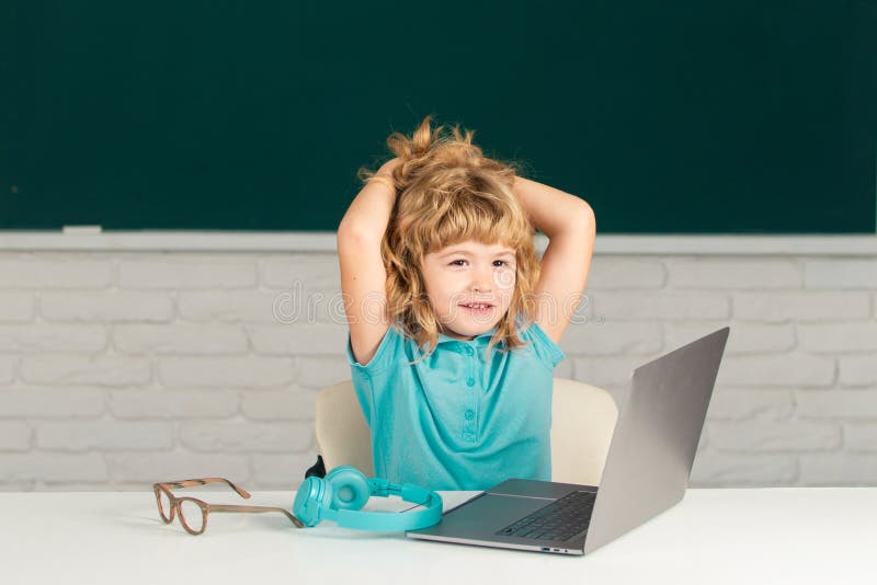 School boy learn lesson sitting at desk, studying online e-learning use internet. Education and knowledge modern stock images
