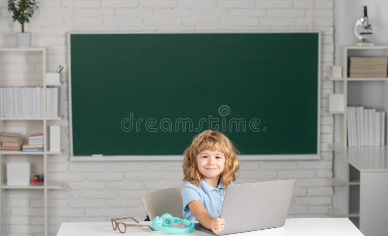 School boy learn lesson sitting at desk, studying online e-learning using internet. Education and knowledge modern stock photography