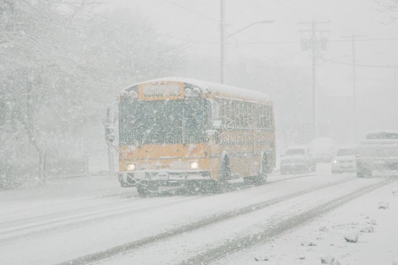 Classico pubblico di autobus della scuola guida in discesa ghiacciata strada durante la tempesta di neve.