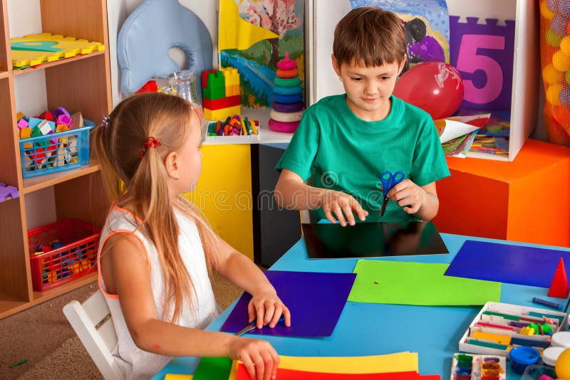 School children with scissors in kids hands cutting paper .