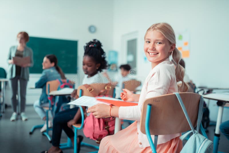 Cheerful girl turning back to talk to her classmate. royalty free stock photo Cheerful girl turning back to talk to her classmate. royalty free stock photo