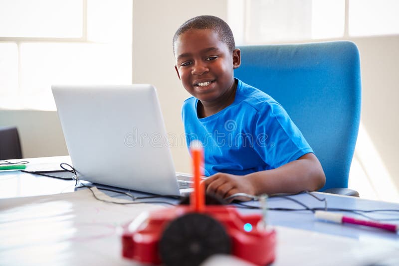 In After School för manlig student som dator kodifierar grupp som lär att programmera robotmedlet arkivbild