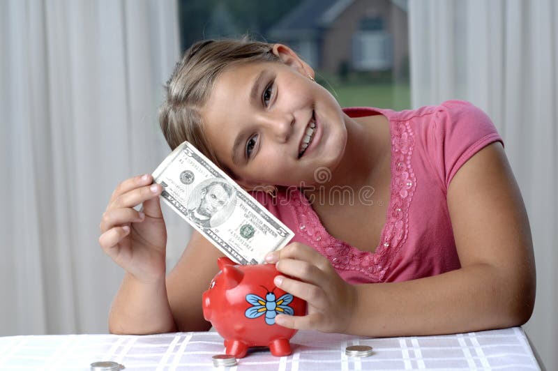 School girl is playing with a paper bills before putting them into the piggy bank. School girl is playing with a paper bills before putting them into the piggy bank..