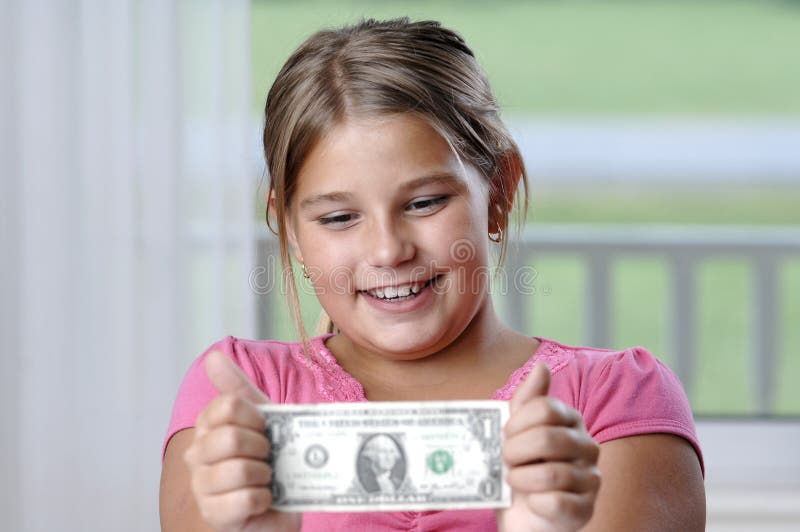 School girl is playing with a paper bills before putting them into the piggy bank. School girl is playing with a paper bills before putting them into the piggy bank..