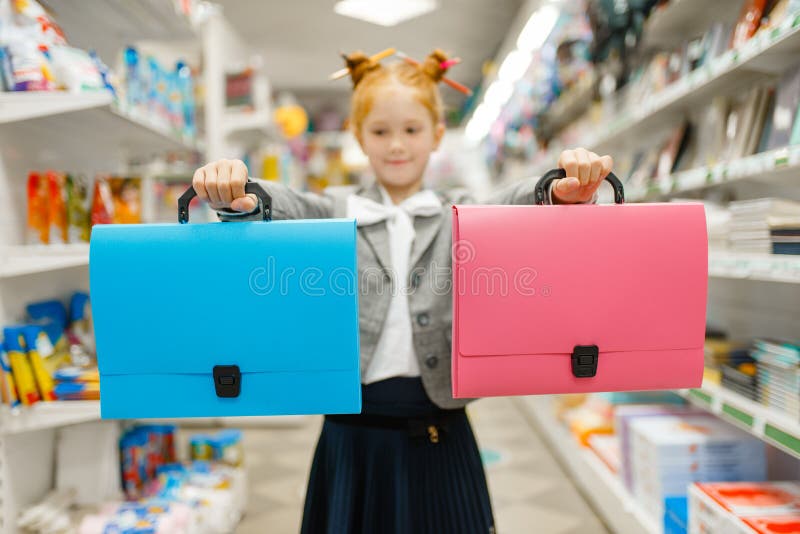 School girl with two folders in stationery store.