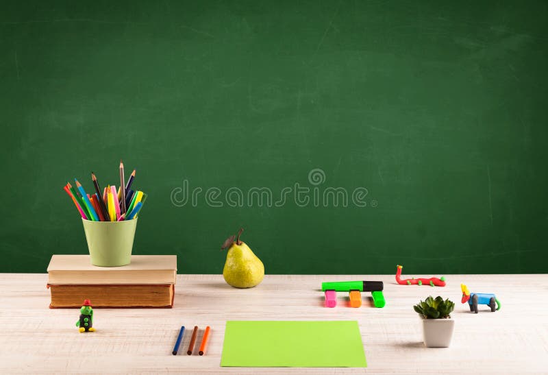 School items on desk with empty chalkboard royalty free stock image