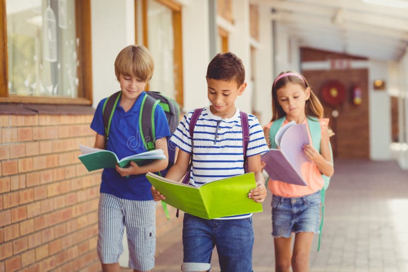 School Kids Reading Books while Walking in Corridor Stock Image - Image ...