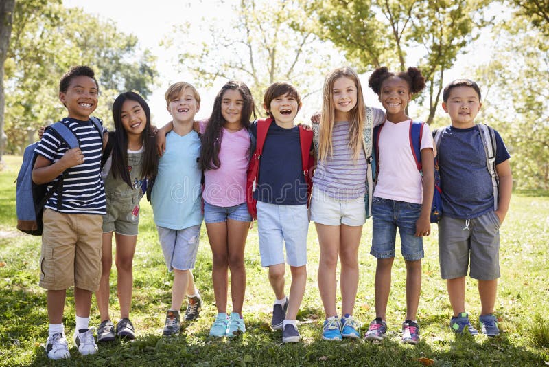 School kids stand embracing in a row outdoors, full length royalty free stock photo