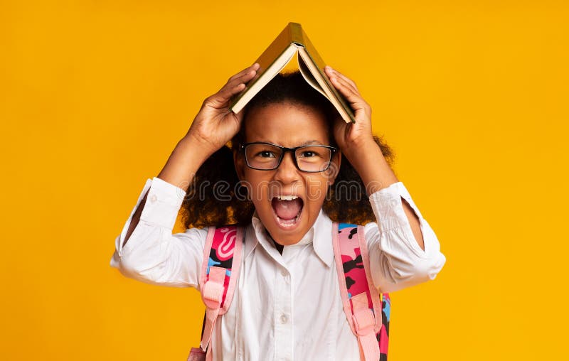 Stressed Schoolgirl Screaming Covering Head With Book Over Yellow Background royalty free stock photos Stressed Schoolgirl Screaming Covering Head With Book Over Yellow Background royalty free stock photos