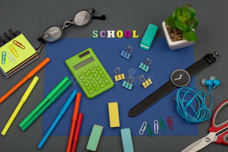 School set with blue paper, text & x22;School& x22; of wooden letters, calculator, markers, eyeglasses, watch and other stationery