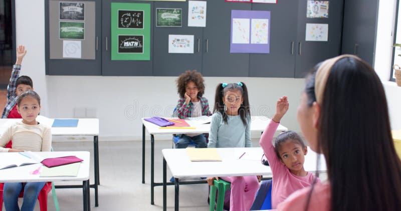 In school, students raising hands in classroom, engaging with teacher stock footage