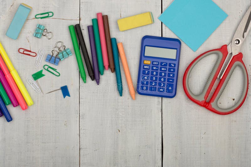 School supplies - scissors, stickers, calculator, crayons, eraser, markers and other accessories on white wooden table