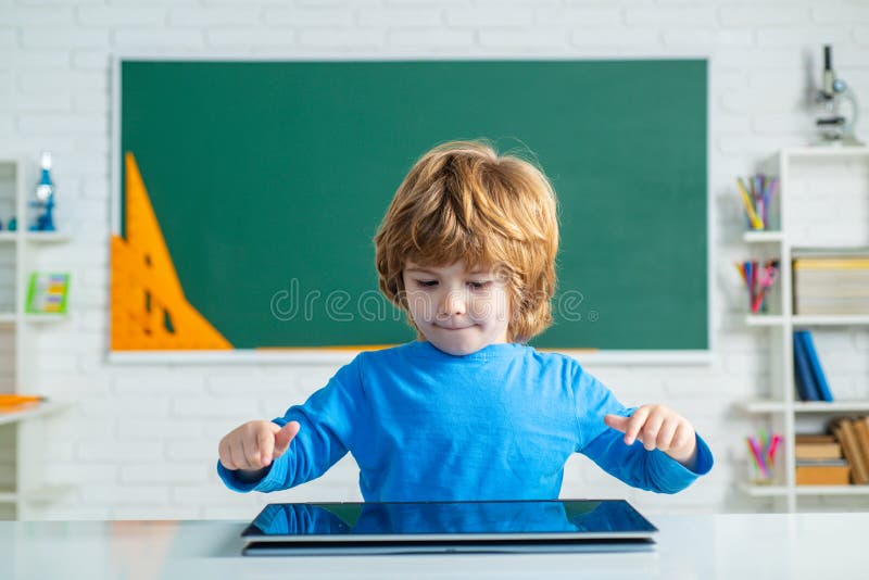 Schoolboy with digital tablet in school classroom. Little boy playing with digital tablet. Kid gets ready for school. stock images