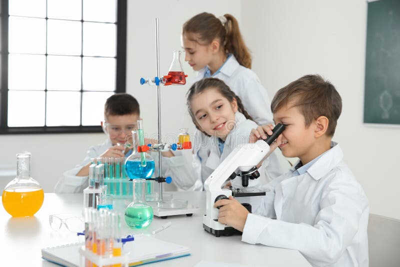 Schoolboy looking through microscope and his classmates royalty free stock photos Schoolboy looking through microscope and his classmates royalty free stock photos