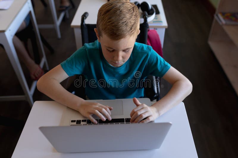 Schoolboy Sitting At A Desk Using A Laptop Computer Stock Image