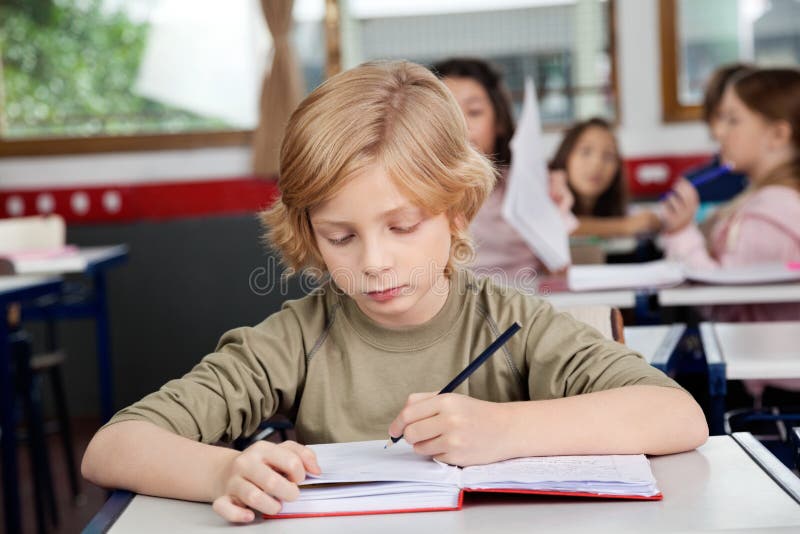 Schoolboy Writing In Book At Desk royalty free stock photo