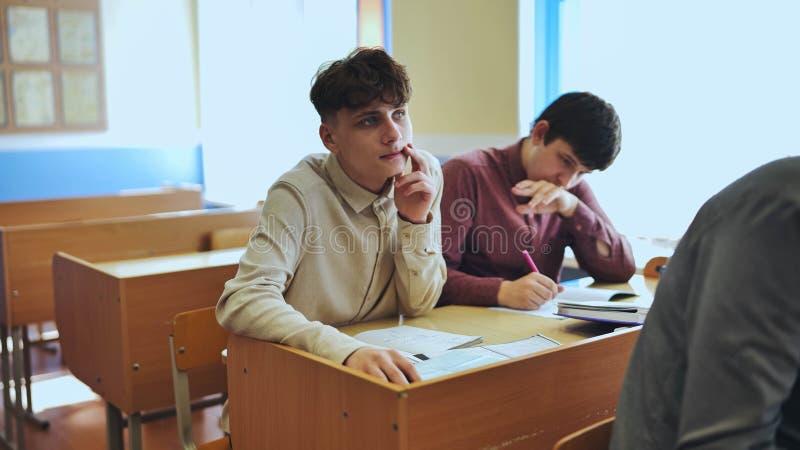 Schoolboys at a desk during class. The boy eats an apple. royalty free stock photo