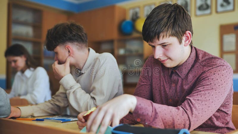 Schoolboys at a desk during class. The boy eats an apple. stock photography